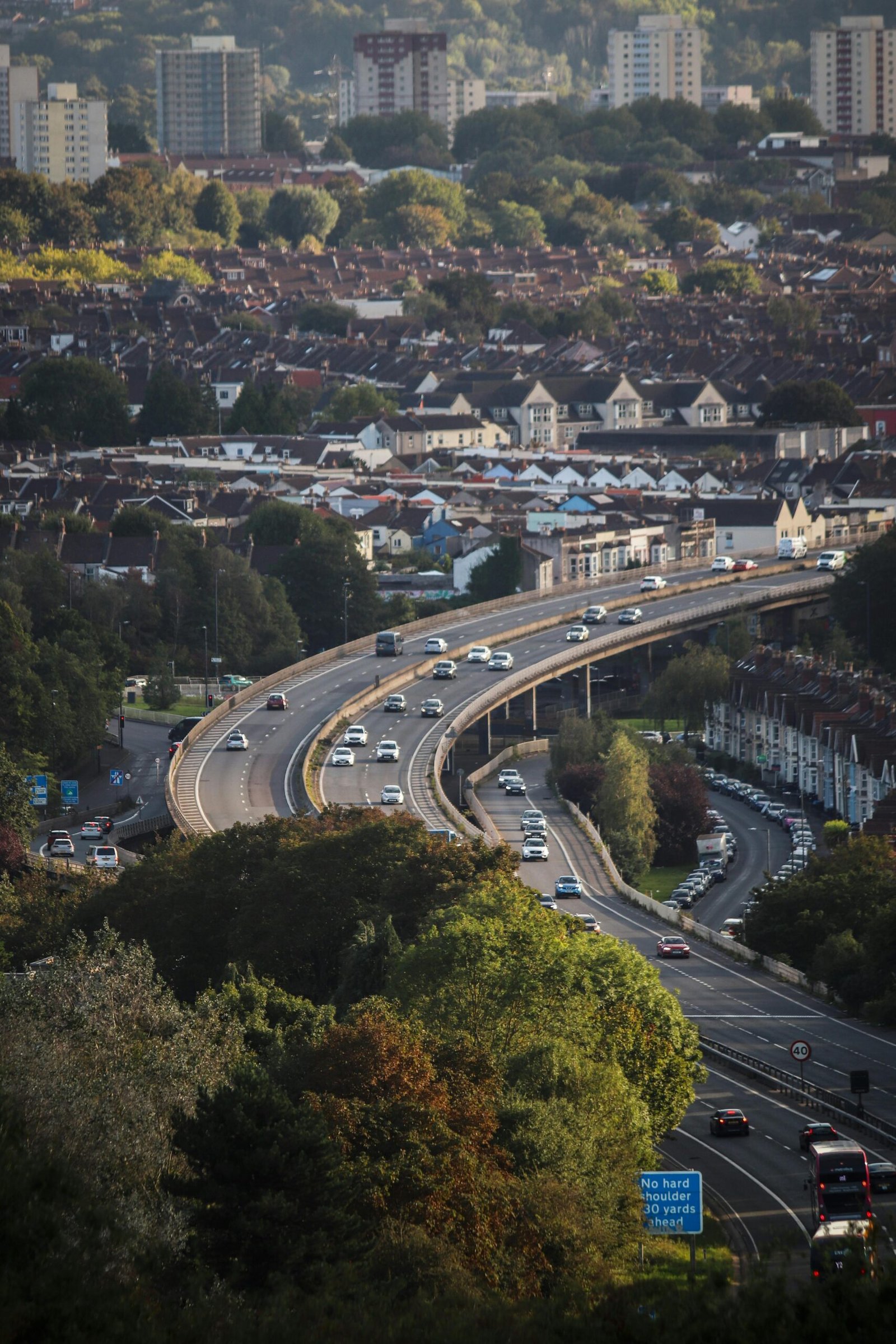 Aerial view of Bristol, England showcasing a busy highway amidst autumn foliage and urban structures.
